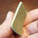 Auf diesem Bild ist die Innenseite der Scherbe zu sehen. Diese ist heller und zeigt kleine regelmäßige Rillen.